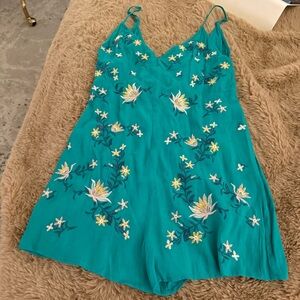 teal-colored romper featuring spaghetti straps and intricate white and yellow